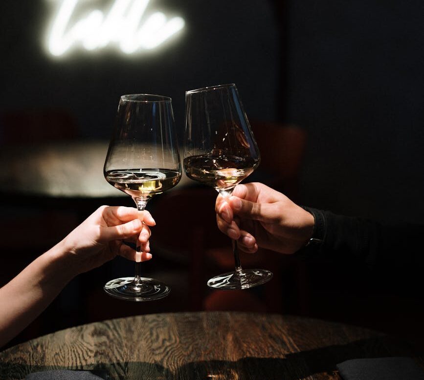Two people clinking wine glasses in a warmly lit restaurant, creating a romantic ambiance.